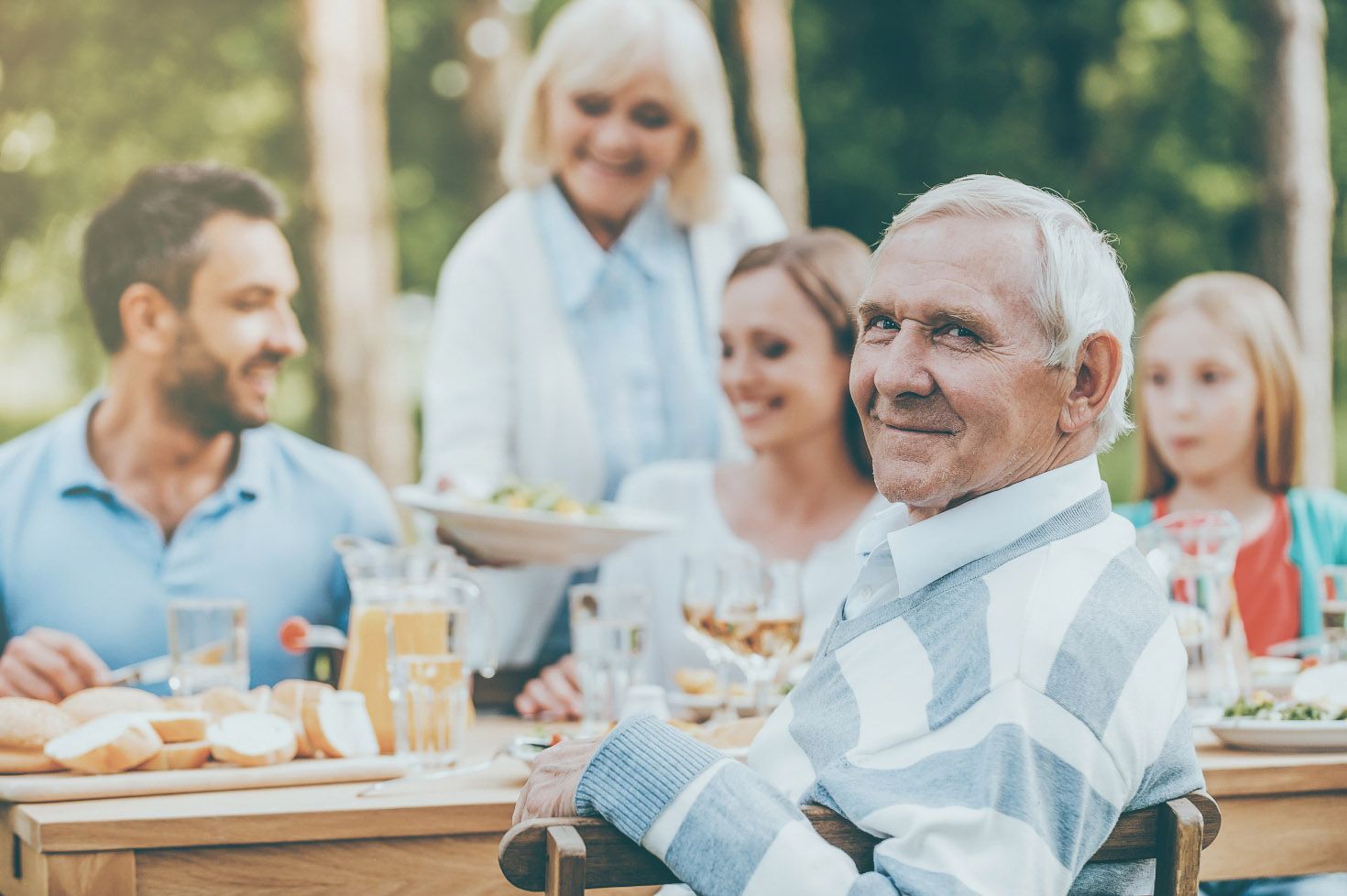 An elderly man enjoying quality time with his loved ones around a table, radiating warmth and togetherness.