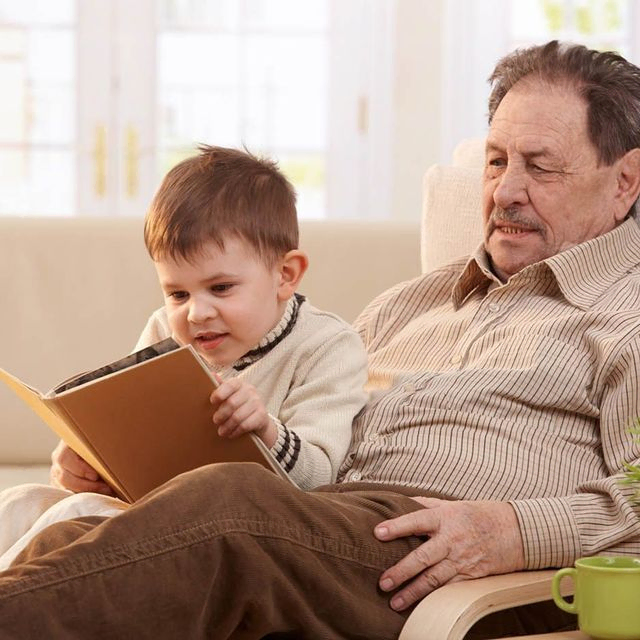 A heartwarming moment captured: A wise grandfather engrossed in a book, sharing stories with his attentive grandson.