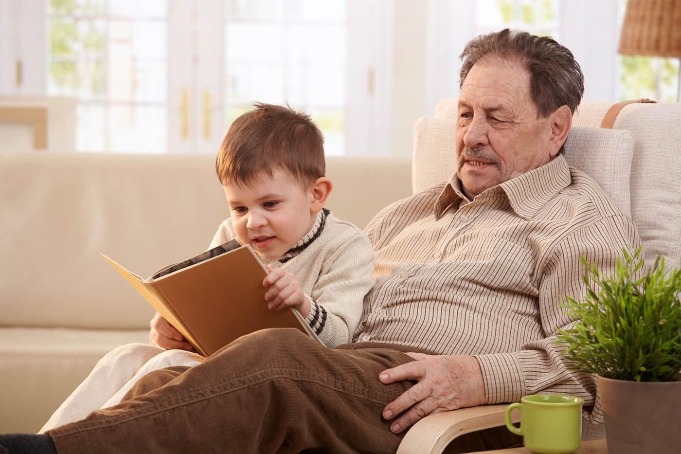 A heartwarming moment captured: A wise grandfather engrossed in a book, sharing stories with his attentive grandson.
